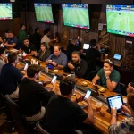 Engaged sports fans using 789win app while watching live matches in exciting bar atmosphere.