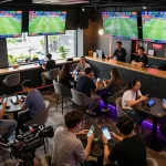 Betting enthusiasts analyzing kèo nhà cái at an energetic sports betting venue with screens displaying live games.